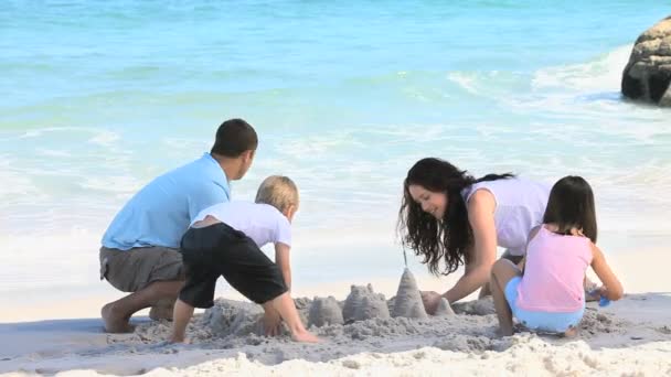 Família feliz construindo um castelo de areia — Vídeo de Stock