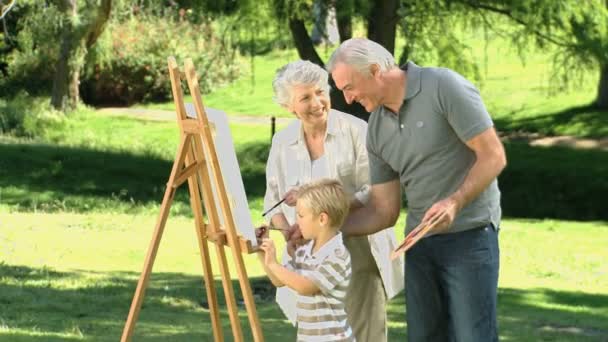 Мальчик рисует холст со своими бабушкой и дедушкой — стоковое видео