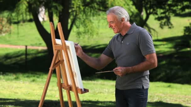 Old male painting a canvas — Stock Video