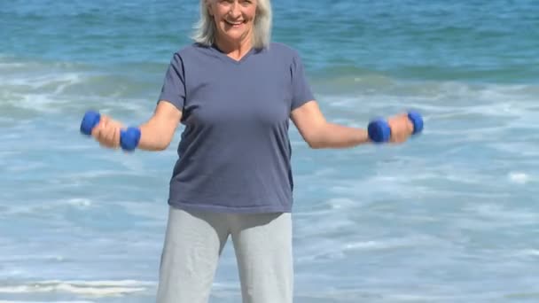 Femme âgée travaillant ses muscles avec des haltères — Video