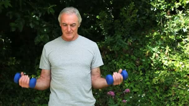 Vieil homme travaillant ses muscles avec des haltères — Video