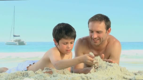 Vater hilft seinem Sohn beim Bau einer Sandburg — Stockvideo