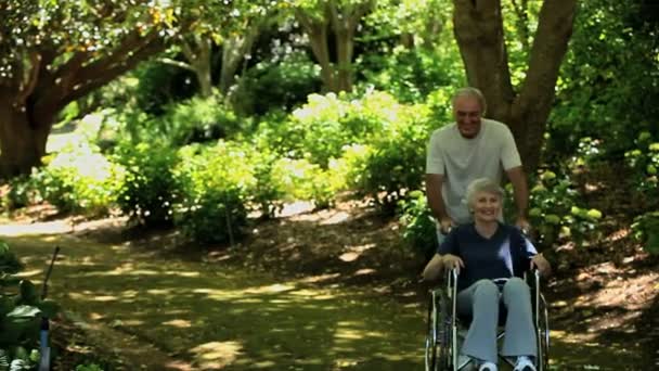 Uomo passeggiando con sua moglie su una sedia a rotelle — Video Stock