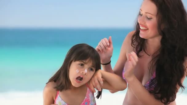 Beautiful mother putting sunscreen on her daughter — Stock Video