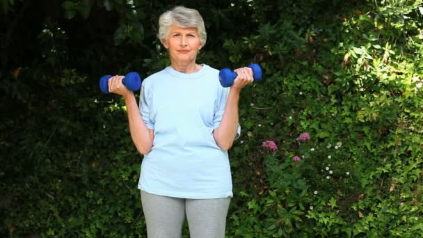 Mulher velha trabalhando seus músculos com halteres — Vídeo de Stock