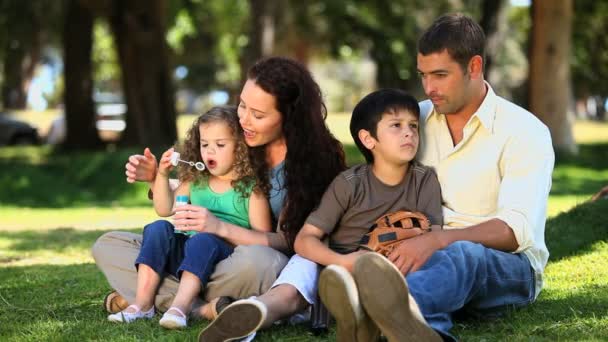 Familia disfrutando del tiempo juntos sentados en la hierba — Vídeo de stock