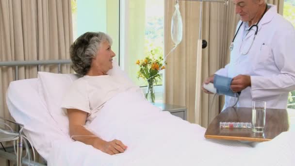 Old doctor measuring blood pressure at his female patient — Stock Video