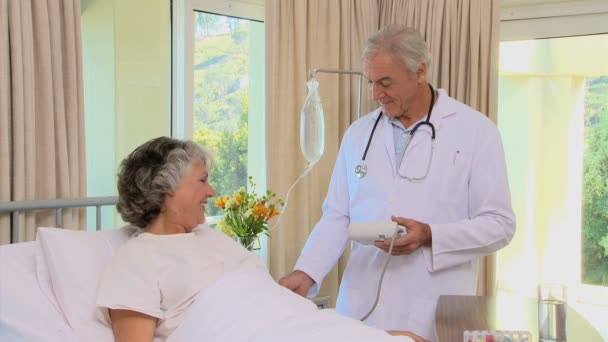Старый доктор проверяет кровяное давление пациента — стоковое видео