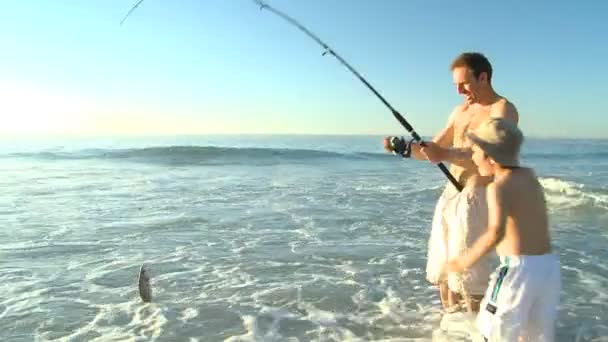 Uomo pesca con suo figlio sulla spiaggia — Video Stock