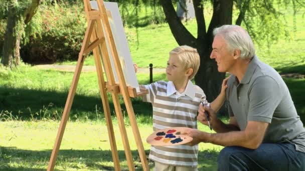 Young child painting a canvas with grandfather — Stock Video