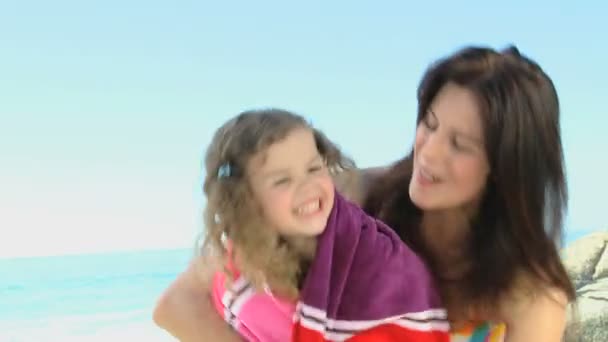 Приваблива жінка обіймає свою дочку пляжним рушником — стокове відео