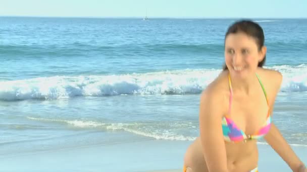 Aantrekkelijke vrouw frisbee spelen op het strand — Stockvideo