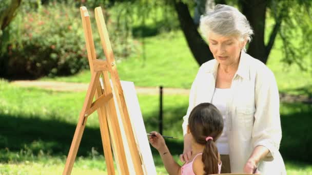 Ung jente som maler lerret med bestemor – stockvideo