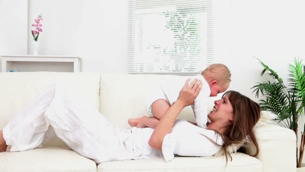 ソファの上に赤ちゃんと一緒に遊んで女性 — ストック動画