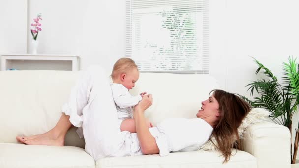 Woman lying on the sofa while holding a baby — Stock Video