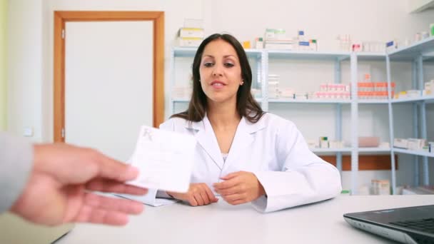 Happy female pharmacist receiving a prescription from a customer — Stock Video