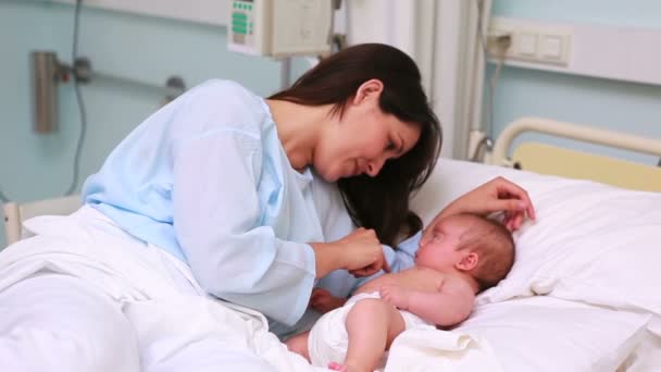 Sonriente madre con su bebé en una cama — Vídeos de Stock