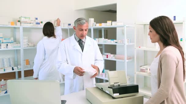 Farmacéutica dando una bolsa de pastillas a una clienta — Vídeo de stock