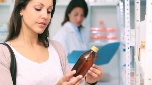 Клиент в аптеке держит бутылку с лекарством — стоковое видео