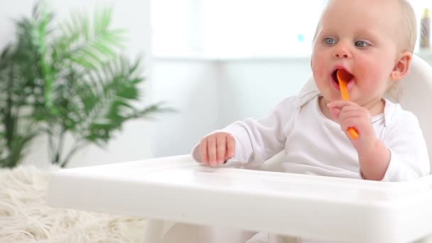 Bebé sentado y agitando cuchara naranja — Vídeos de Stock