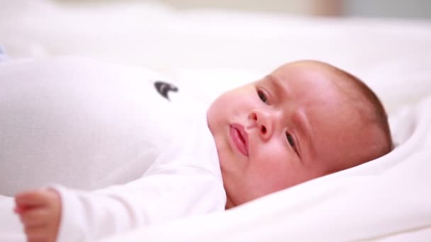 Pasgeboren baby in luiers liggen op een bed met dekens — Stockvideo