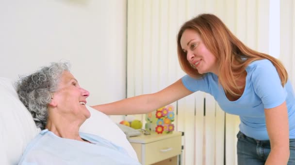 Leende kvinna håller handen på en patient i ett rum — Stockvideo