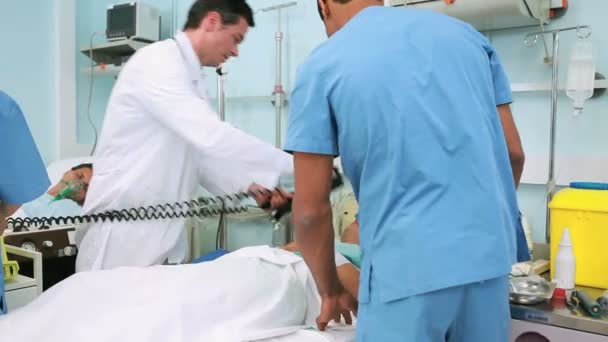Läkare med en defibrillator på medvetslös patient — Stockvideo