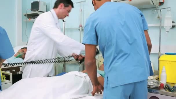 Médecin utilisant un défibrillateur sur un patient inconscient — Video