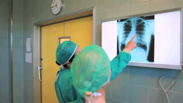 Два хирурга смотрят на рентген — стоковое видео