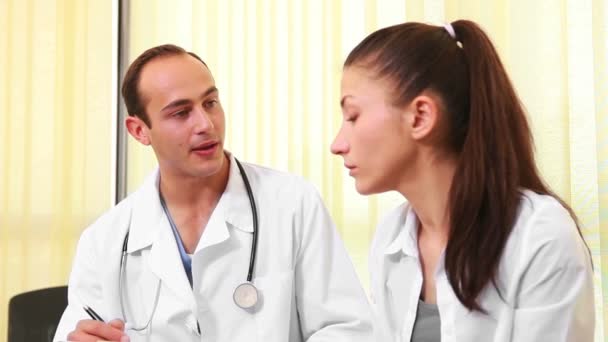 Doctor talking to a woman while they sit in a waiting room — Stock Video