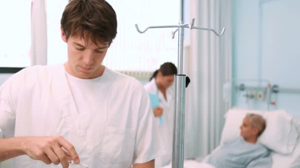 Male nurse placing a bag on a drip stand — Stock Video