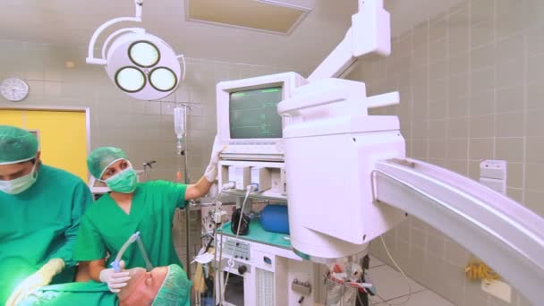 Медсестра регулирует монитор рядом с пациентом — стоковое видео