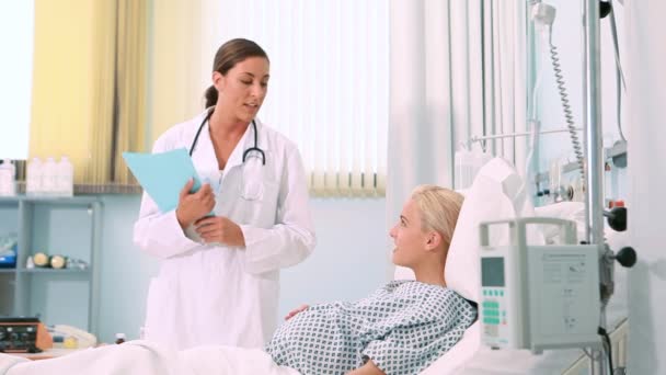 笑みを浮かべて妊娠中の女性を話している女性の産科医 — ストック動画