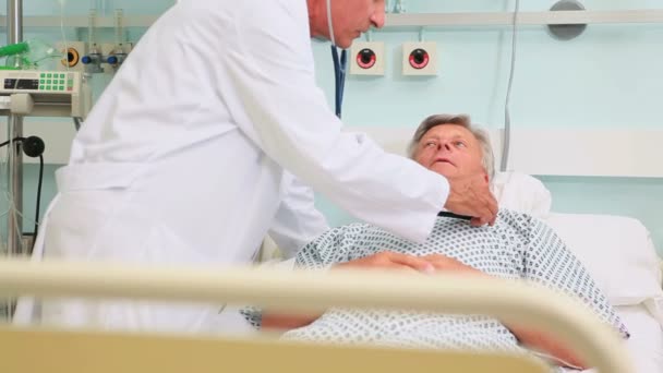 Médico masculino auscultando a un paciente masculino en una sala de camas — Vídeos de Stock