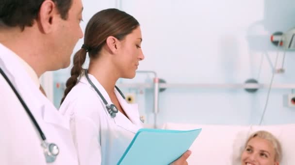 Два практикующих врача стоят рядом с пациентом — стоковое видео