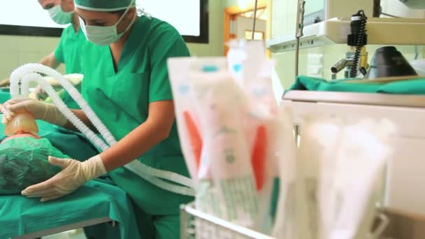 Женщина-хирург надевает кислородную маску на лицо пациентки без сознания — стоковое видео