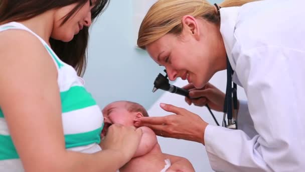 Mère tenant un bébé dans une salle d'examen avec une femme médecin — Video