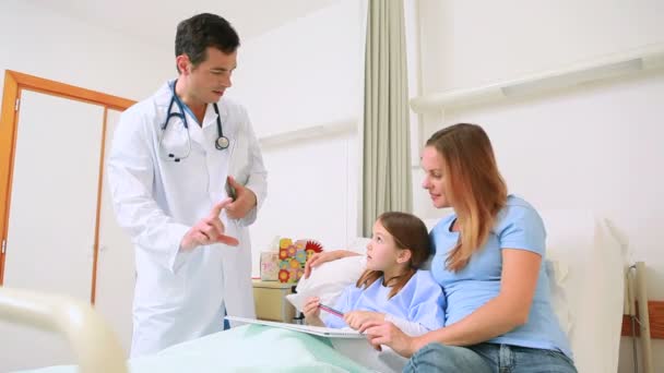 Улыбающийся доктор осматривает маленькую девочку в больничном отделении — стоковое видео