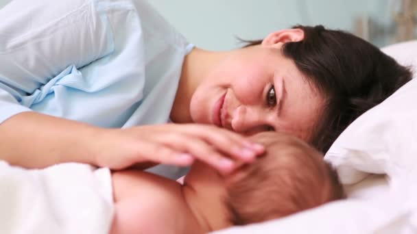 Mutter blickt ihr schlafendes Baby Kopf an Kopf in einem Bett an — Stockvideo