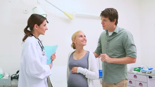 Doctor talking to a pregnant woman and her husband — Stock Video