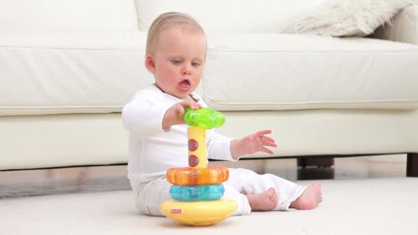 Bebê sentado e brinca com brinquedo — Vídeo de Stock