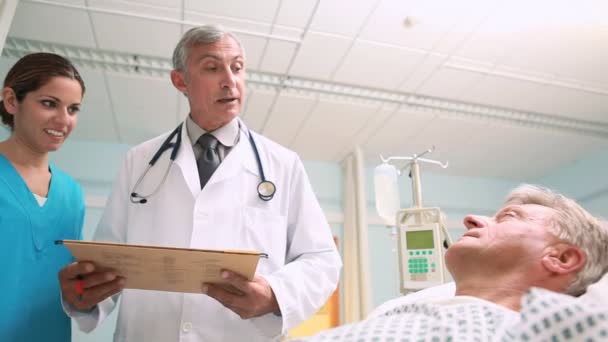 Medizinisches Team im Gespräch mit einem Patienten auf einer Bettenstation — Stockvideo