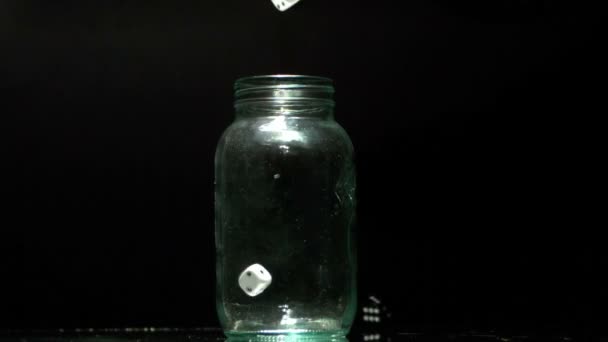 Black and white dice falling into glass jar — Stock Video