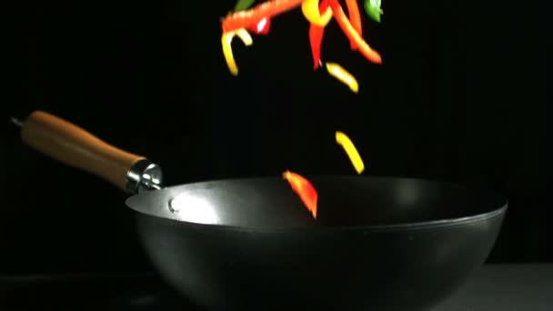 Pimentos mistos caindo em wok no fundo preto — Vídeo de Stock