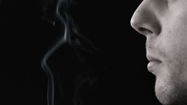 Человек курит сигареты в черно-белом — стоковое видео