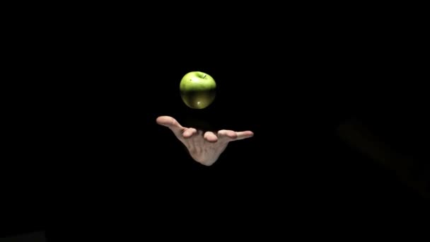 Hand tossing a green apple on a black background — Stock Video