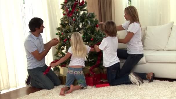 Montaje de una familia decorando un árbol de navidad — Vídeos de Stock