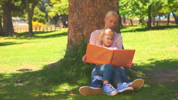 Jovencita leyendo un libro con su hija — Vídeos de Stock