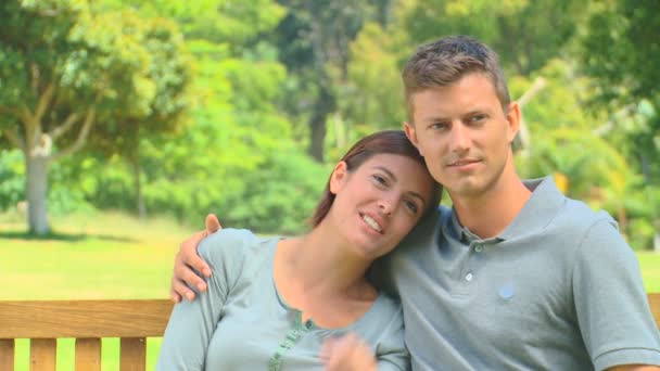 Young couple talking on a park bench — Stock Video