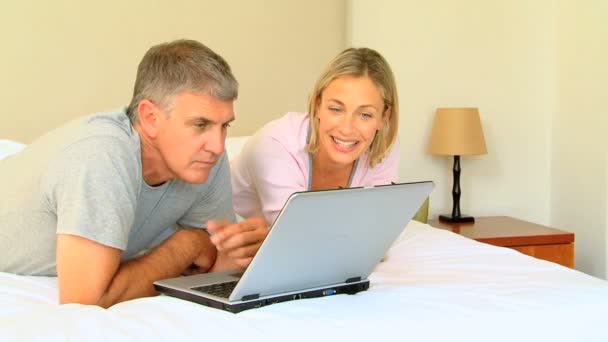 Casal relaxante na cama com um laptop — Vídeo de Stock